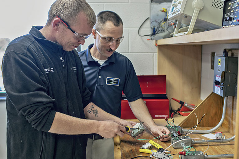 two men working on an electrical board