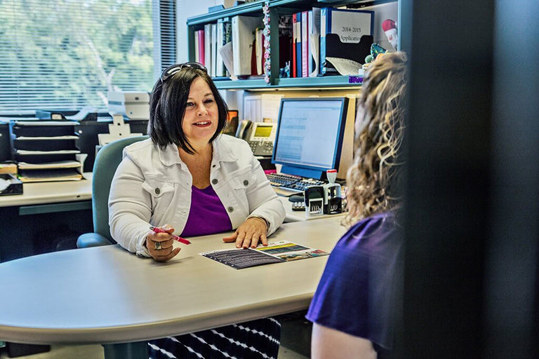 two people sitting across from a desk