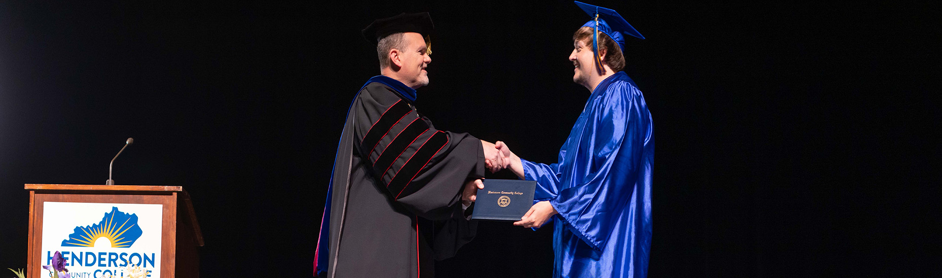 Dr. Warren handing a student his diploma during graduation